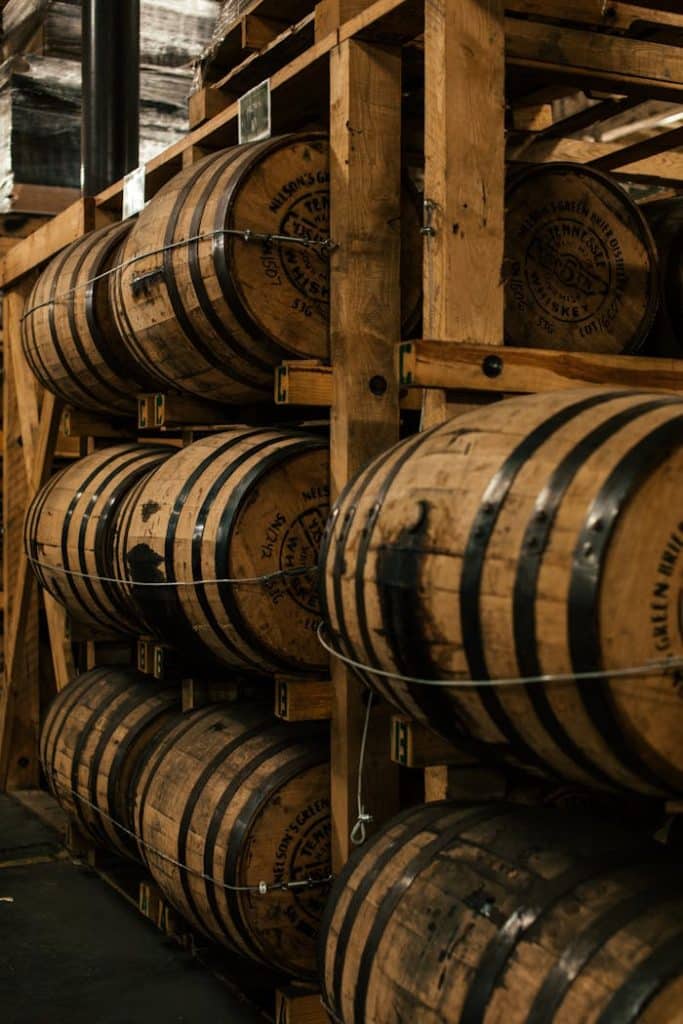 A vertical shot of wooden barrels neatly stacked in a distillerys storage room.