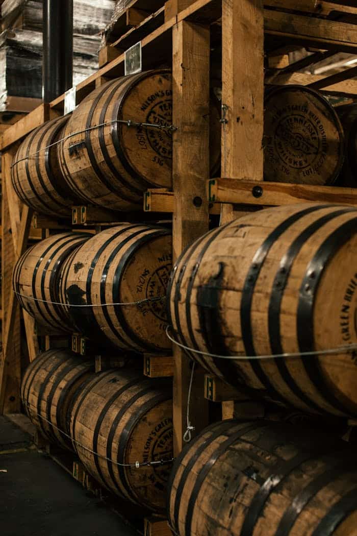 A vertical shot of wooden barrels neatly stacked in a distillerys storage room.